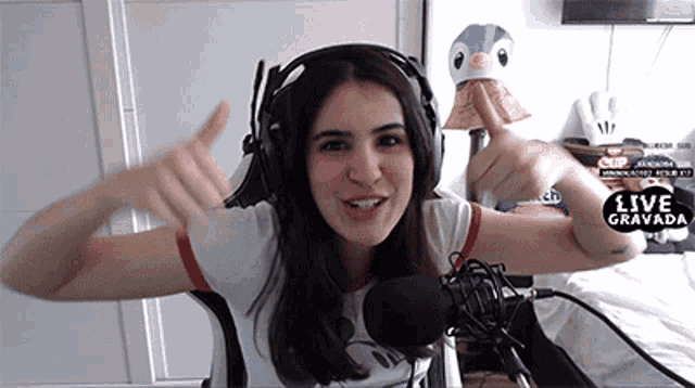 a woman wearing headphones giving a thumbs up in front of a microphone with the words live gravada on the bottom