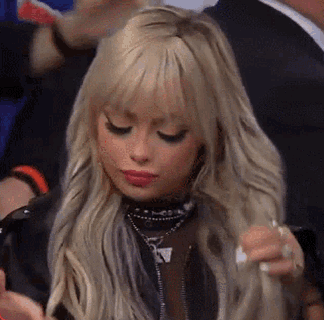 a woman with blonde hair and bangs is sitting in a stadium .