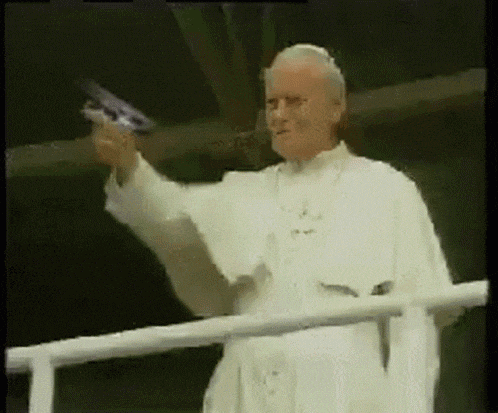 a man in a white robe is holding a gun in his hand while standing on a balcony .