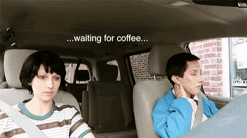 a man and a woman are sitting in a car waiting for coffee