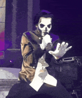 a man in a skull mask is holding a microphone on a stage .