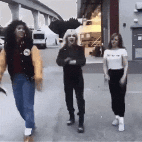 a group of people are walking down a street with one wearing a varsity jacket