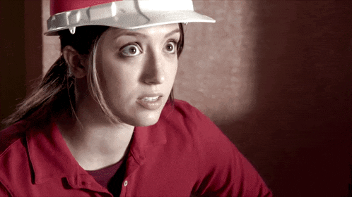 a woman wearing a hard hat looks surprised