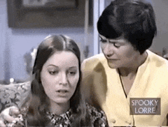 two women are sitting on a couch talking to each other .
