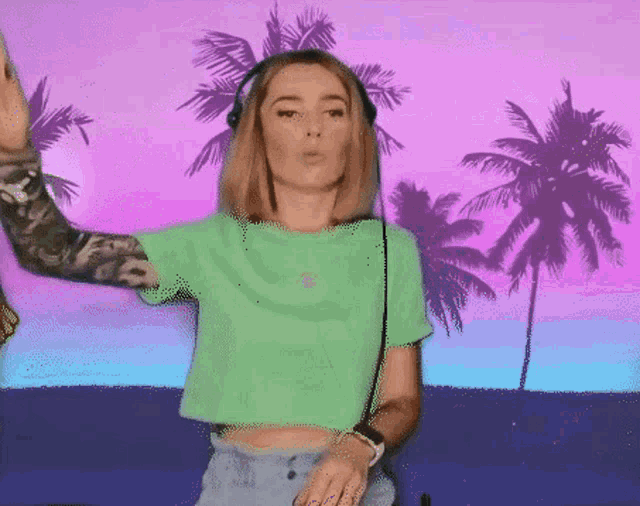 a woman in a green shirt is wearing headphones and dancing
