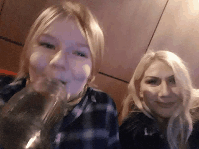 a woman drinking from a bottle next to a girl