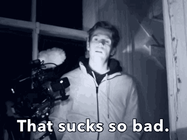a man holding a camera with the words that sucks so bad above him