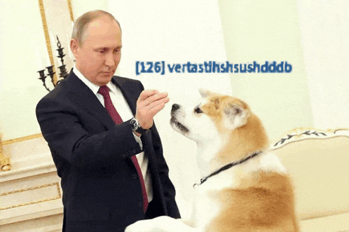a man in a suit and tie petting a dog in front of a wall that says [ 126 ]