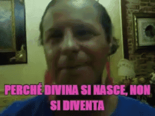 a woman in a blue shirt with pink earrings says " perche divina si nasce non si diventa "