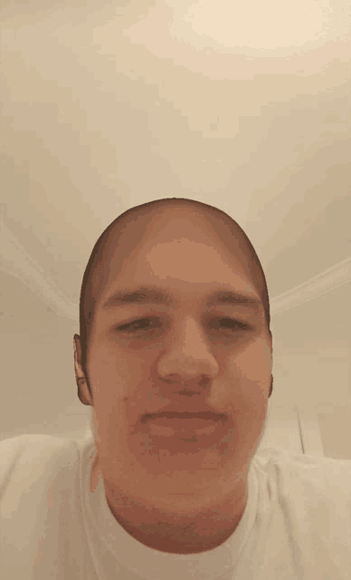 a young man with a shaved head looks at the camera