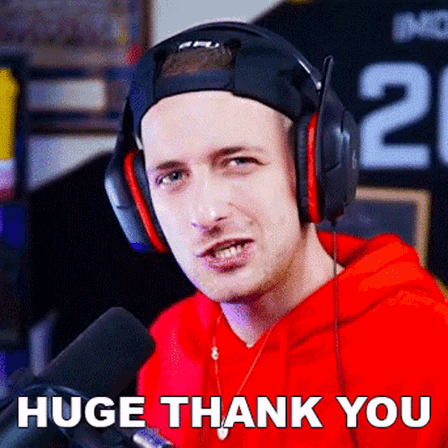 a man wearing headphones says " huge thank you " in front of a microphone