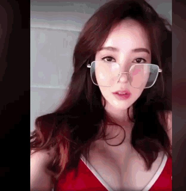 a woman wearing glasses and a red top takes a selfie