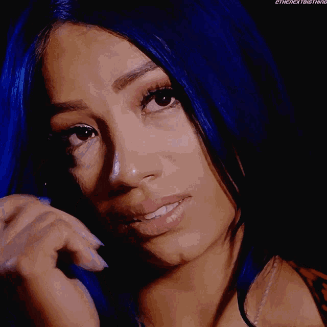 a woman with blue hair wipes her eyes with a tear