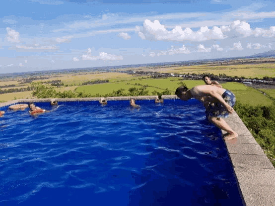 a man is diving into a large blue pool