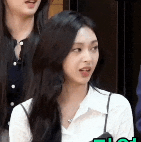 a woman with long black hair is wearing a white shirt and a black tank top .