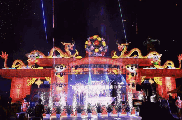 fireworks are being displayed in front of a stage with a dragon on top