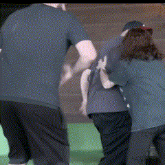 a man in a blue shirt is pushing a woman in a black shirt