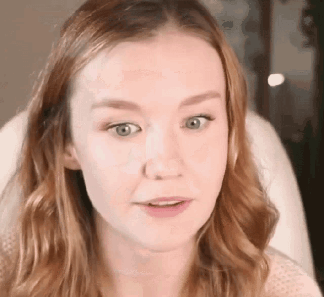 a close up of a woman 's face with long red hair and blue eyes .