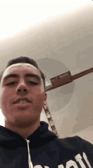 a young man wearing a black hoodie with the letter m on it takes a selfie