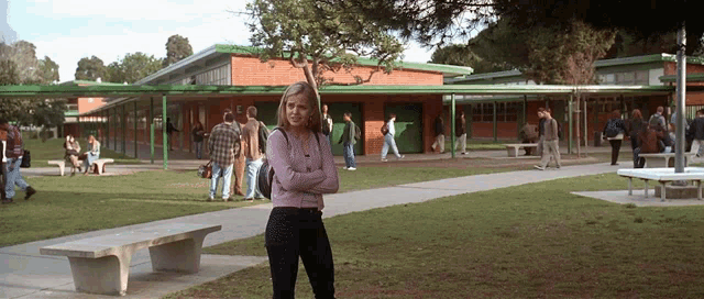 a woman with her arms crossed stands in front of a school