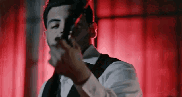 a man in a suit is shaving his face with a razor in a dark room .