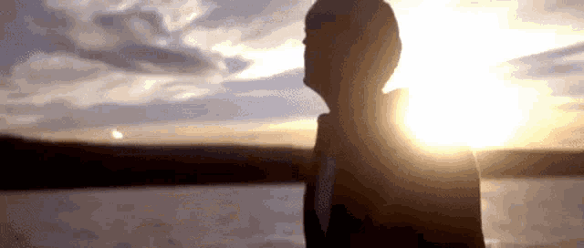 a silhouette of a person standing in front of the sun