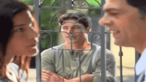 a man and a woman are looking through a gate at a man behind it