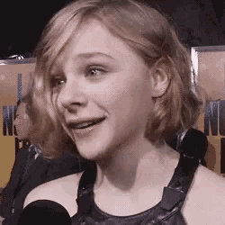 a close up of a woman talking into a microphone and smiling .