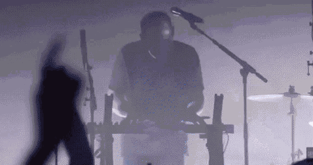 a man is playing a keyboard and singing into a microphone on a stage