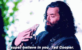 a man with long hair and a beard is holding a bird and saying " i super believe in you tad cooper "