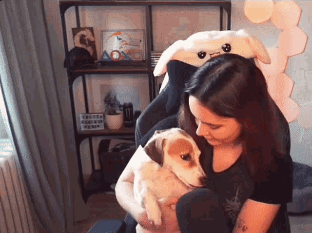 a woman is holding a puppy in her arms while sitting in a chair