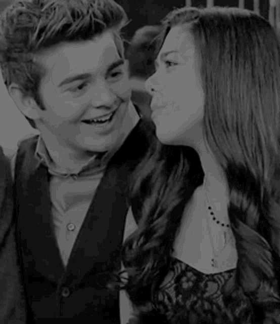 a black and white photo of a boy and a girl kissing each other .