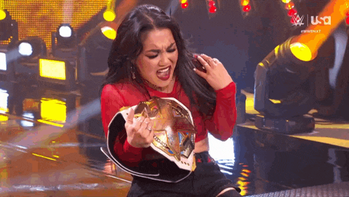 a woman in a red shirt is holding a championship belt