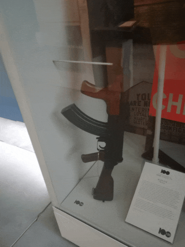 a gun in a glass case next to a sign that says " you are not entering "