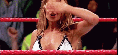a woman in a bikini is standing in a wrestling ring covering her eyes .