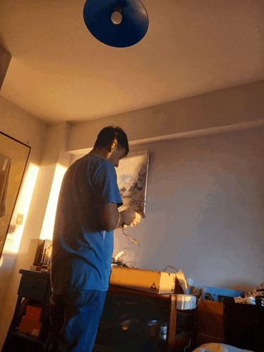 a man in a blue shirt is standing in front of a painting