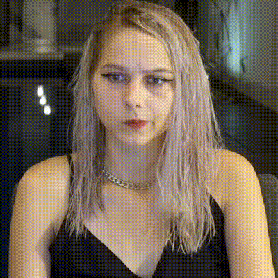 a woman with long blonde hair is wearing a black tank top and a chain around her neck .