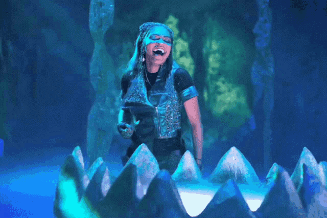 a woman in a blue costume is standing in front of a shark 's mouth
