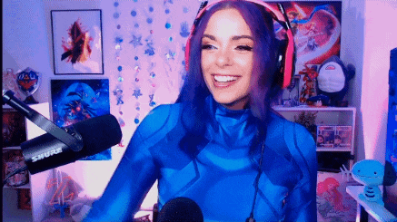 a woman with purple hair is wearing headphones and a blue costume while standing in front of a microphone .