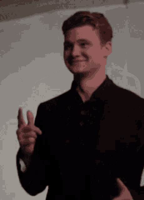 a man in a black shirt is smiling and pointing