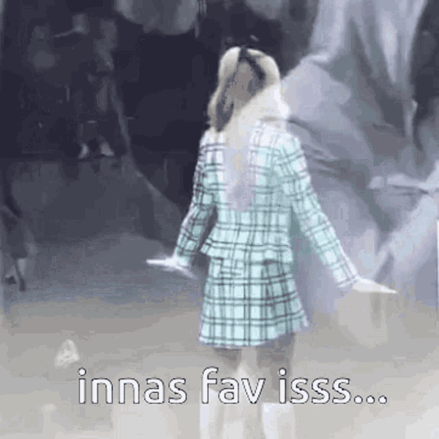 a woman in a plaid jacket is dancing in front of a crowd and the words innas fav isss .