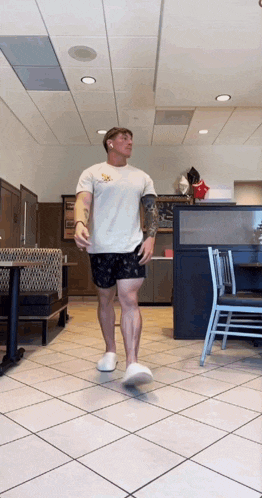 a man wearing shorts and a white shirt is walking through a restaurant
