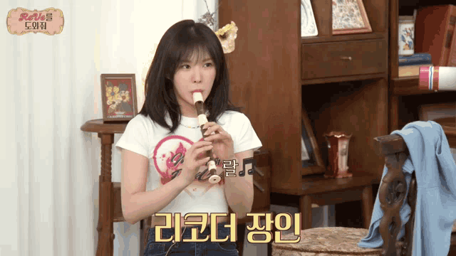 a girl is playing a flute in a room with foreign writing
