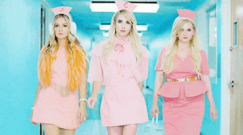 three women dressed as nurses are walking down a hospital hallway .