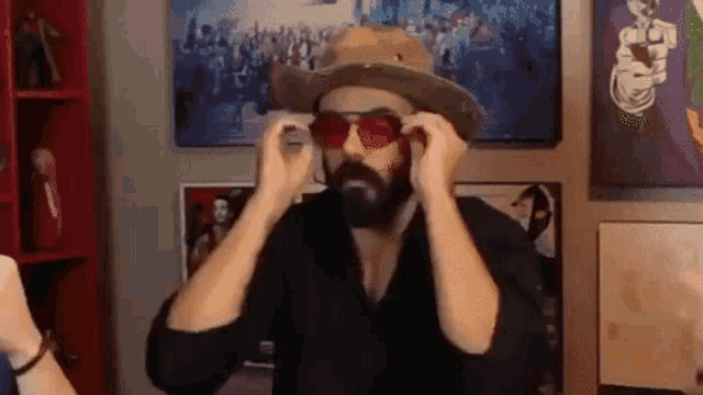 a man with a beard wearing sunglasses and a hat .