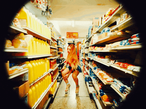 a woman is standing in a grocery store aisle with a sign that says christmas on it