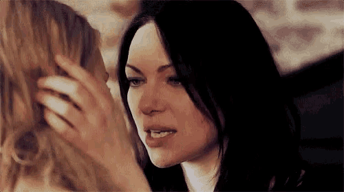 a woman is touching another woman 's face while sitting next to each other .