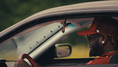 a man in a red hat is driving a white car