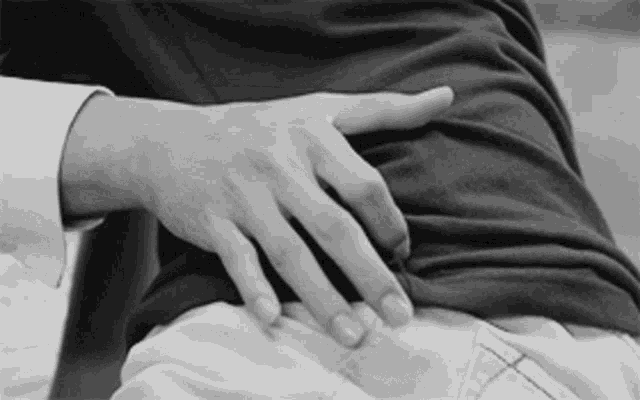 a black and white photo of a person touching another person 's waist