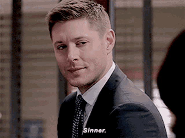 a man in a suit and tie with the word sinner on his chest